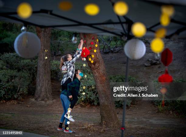 February 26: Amber Day, left, and sister Brooke Day, both 12, decorate a park as fellow neighbors of an Asian-American family that was harassed and...