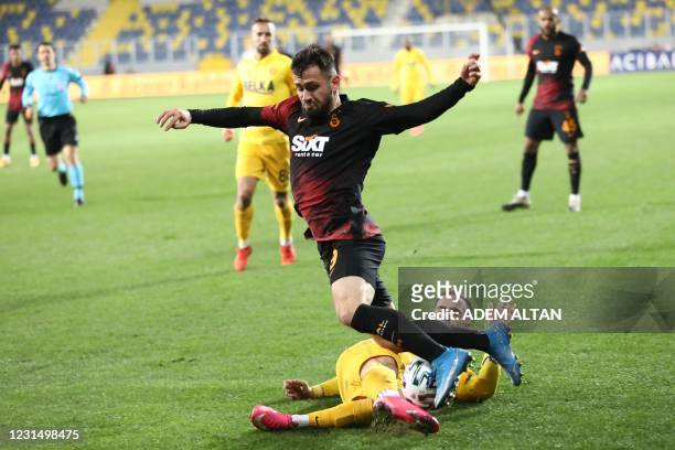 Galatasaray's Turkish defender Omer Bayram is tackled by Ankaragucu's Greek defender Stelios Kitsiou during the Turkish Super Lig week 28 football...