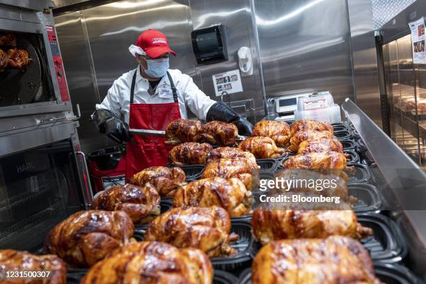 Worker wearing a protective mask removes rotisserie chicken from skewers inside a Costco store in San Francisco, California, U.S., on Wednesday,...