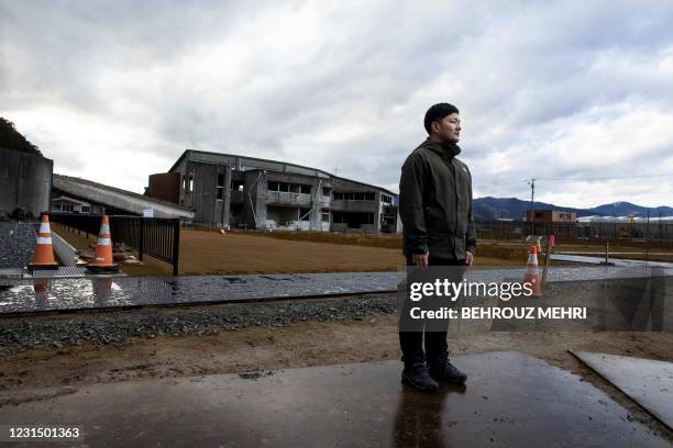 In this picture taken on February 7 tsunami survivor Yuto Naganuma poses in front of the damaged Okawa elementary school, where his younger brother...