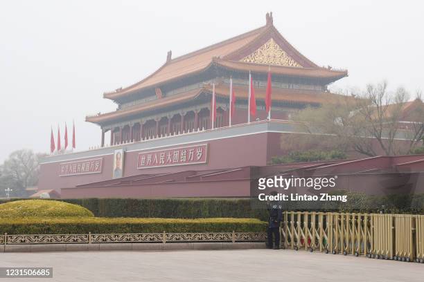 Police officer wears a face mask as he stands guard in front of Tiananmen Gate before the opening ceremony of the fourth session of the 13th National...
