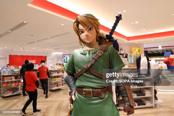 Link figurine from Legend of Zelda with shop staff inside Nintendo Tokyo store in Shibuya.