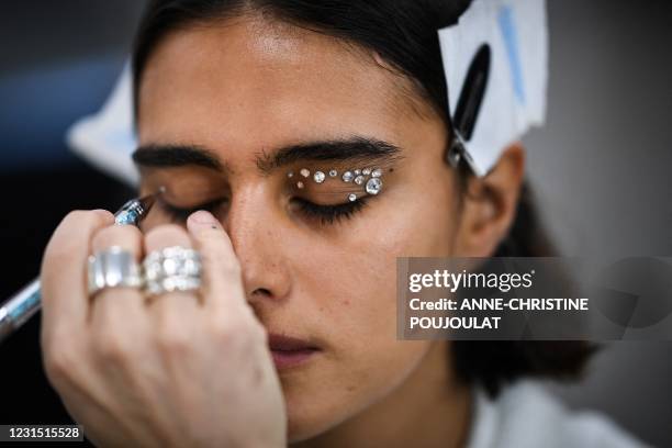 Make-up artist applies rhinestones on the eyelids of a model in the backstage prior to the Coperni AW21 Women's Fall-Winter 2020-2021 Ready-to-Wear...