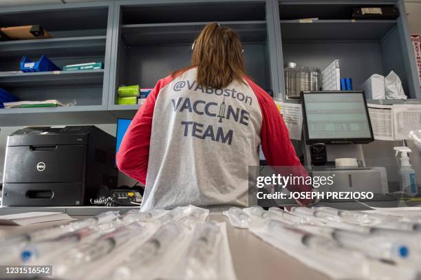 Home base primary care Pharmacist Erin Emonds logs onto a computer before filling syringes with the Johnson & Johnson Janssen vaccine in the allotted...