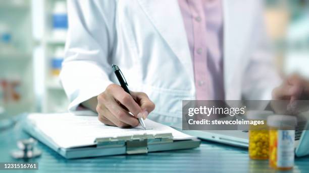 mujer escribiendo notas en la farmacia. - caderno de receitas fotografías e imágenes de stock