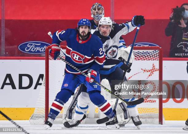 Phillip Danault of the Montreal Canadiens and Tucker Poolman of the Winnipeg Jets battle for position in front of goaltender Connor Hellebuyck during...