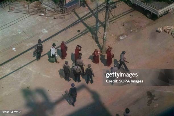 Burmese buddhist monks walk past riot police during a demonstration against the military coup. Myanmar police attacked protesters with rubber...