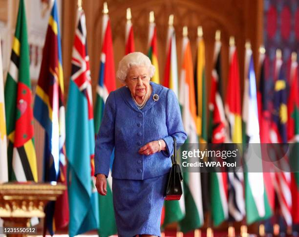 In this undated image released on March 6 Queen Elizabeth II walks past Commonwealth flags in St George's Hall at Windsor Castle, to mark...