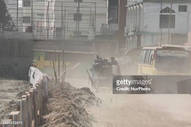 Peoples use a van through a dusty busy road in Dhaka, Bangladesh on March 06, 2021.
