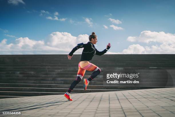 sportlerin sprintet in der stadt - marathon stock-fotos und bilder