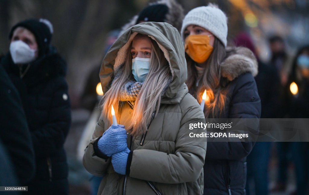 Friends and family of victims holding burning candles,...