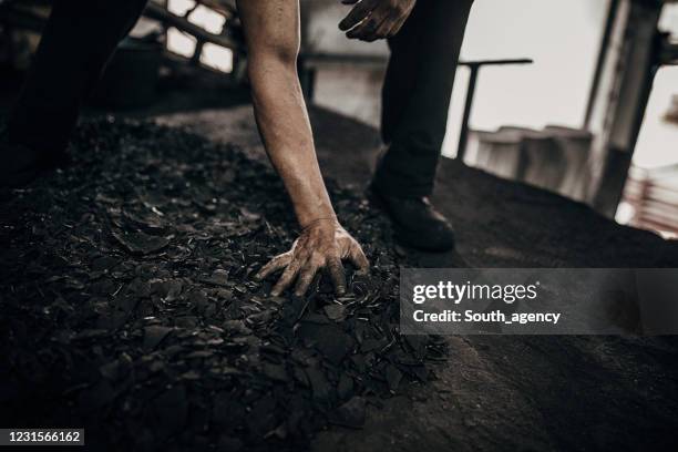 de hand die van de mens zwarte steenkool houdt - briquet stockfoto's en -beelden