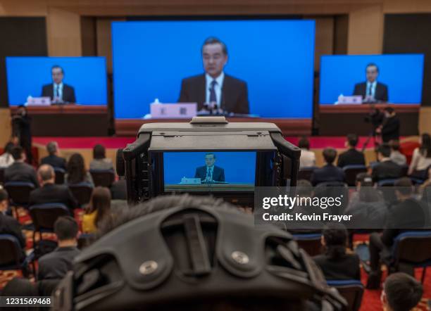 Chinese and foreign journalists watch as China's Foreign Minister Wang Yi, on screen, answers a question during a video news conference, held...