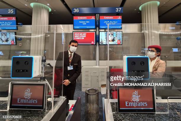 Emirates airlines employees behind check in counters equipped with a fast-track identification system that uses face and iris-recognition...
