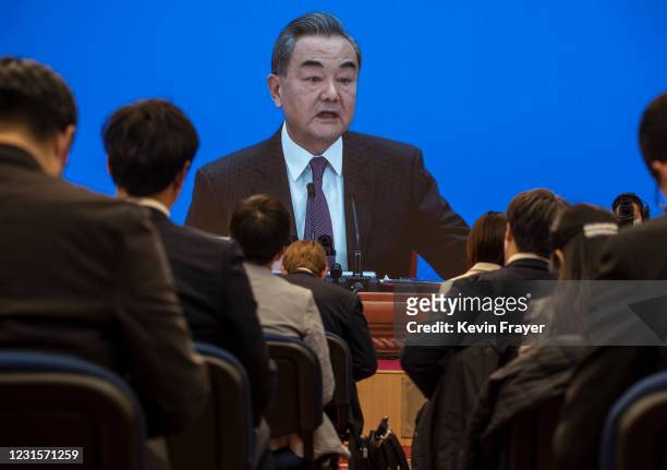 Chinese and foreign journalists watch as China's Foreign Minister Wang Yi, on screen, answers a question during a video news conference, held...