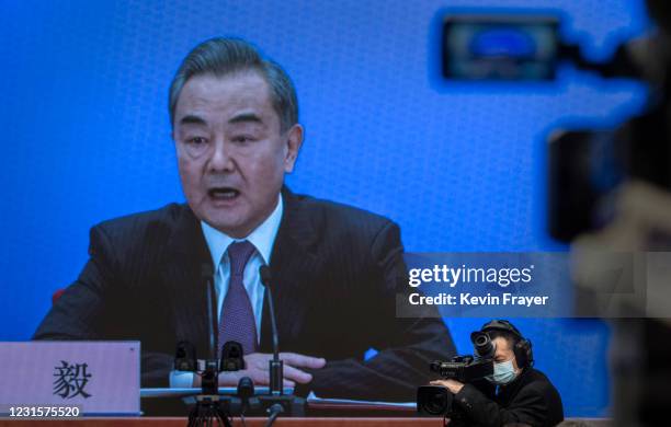 China's Foreign Minister Wang Yi, on screen, answers a question during a video news conference, held remotely as a precaution for COVID-19, as part...