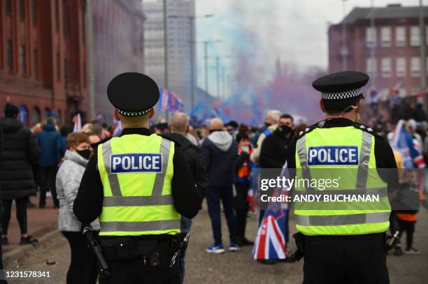 Police officers patrol as Rangers fans celebrate outside Ibrox Stadium, home of Rangers Football Club, in Glasgow on March 7, 2021 after their first...