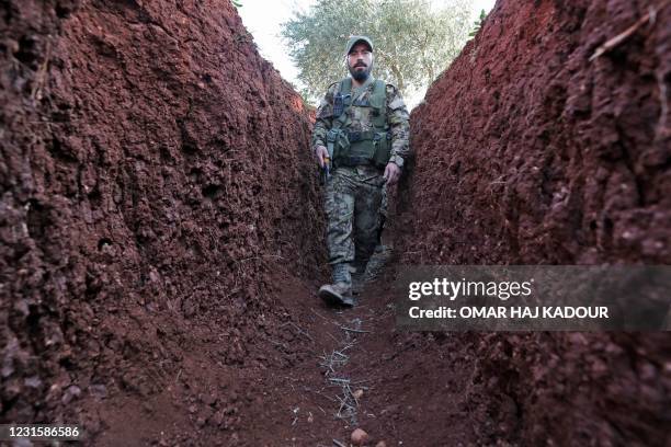 Syrian rebel fighter for the National Liberation Front advances in a trench on the front line facing regime forces from the strategic rebel-held town...