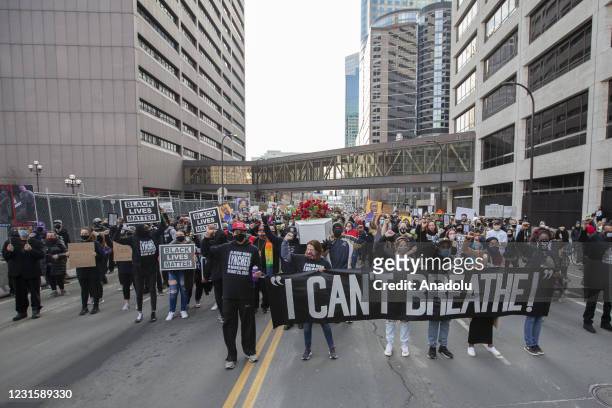Protesters march through the city during a silent march in memory of George Floyd a day before jury selection for the trial of former Minneapolis...