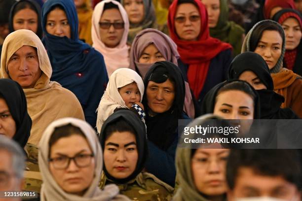 Hazara woman holds her child as she with others attend an event on International Women's Day in Bamiyan Province on March 8, 2021.