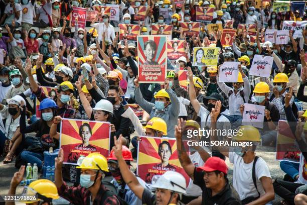 Protesters making three-finger salute while holding portraits of Aung San suu Kyi, during the demonstration against military coup. Myanmar police...