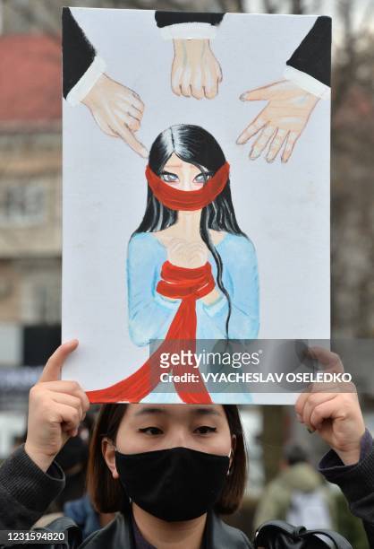 Woman holds a poster during a rally to mark the International Women's Day in Bishkek on March 8, 2021. - Femen activists protested against patriarchy...