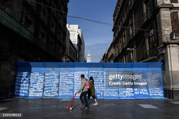 People walk past fences intervened with names of feminicide victims at the historic center ahead of demonstrations as part of the International...