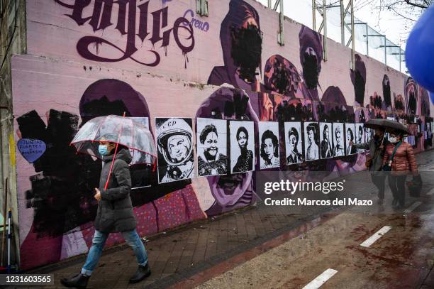 Women walk past by a feminist mural that appeared today vandalized during International Women's Day. Placards of women have been placed over the...