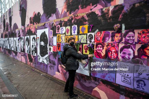 Woman placing flowers in a feminist mural that appeared today vandalized during International Women's Day. Placards of women have been placed over...