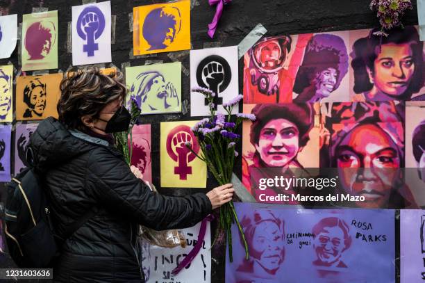 Woman placing flowers in a feminist mural that appeared today vandalized during International Women's Day. Placards of women have been placed over...