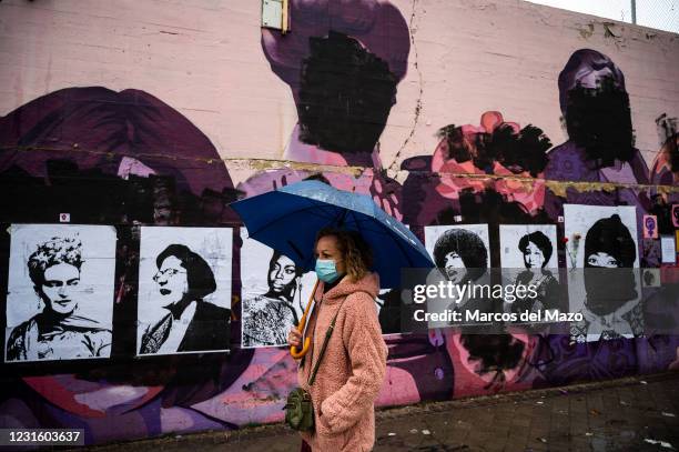 Woman walks past by a feminist mural that appeared today vandalized during International Women's Day. Placards of women have been placed over the...