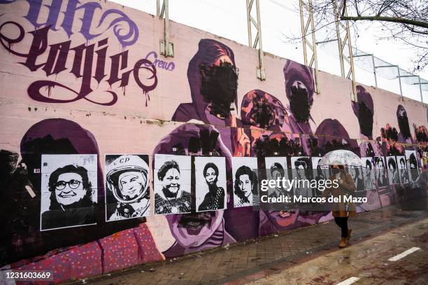 Woman walks past by a feminist mural that appeared today vandalized during International Women's Day. Placards of women have been placed over the...
