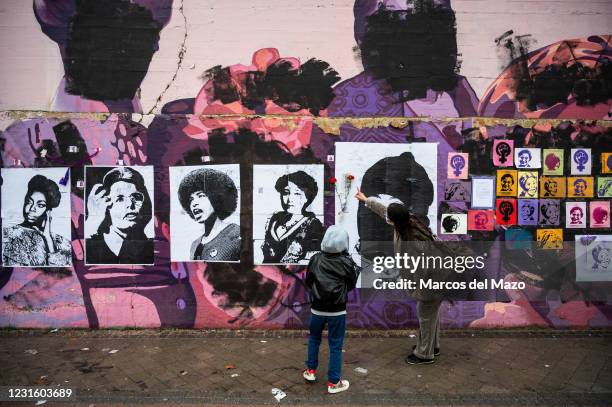 Woman shows her son a feminist mural that appeared today vandalized during International Women's Day. Placards of women have been placed over the...