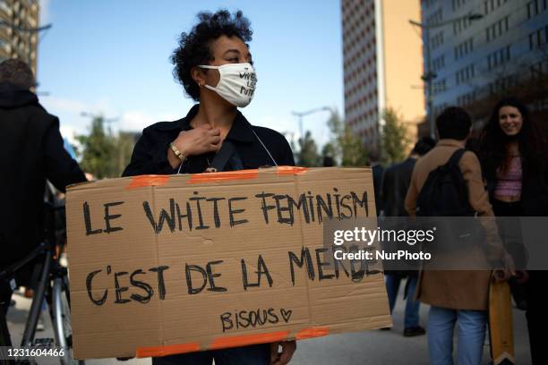 Woman hold a placard reading 'White feminism is shit'. Thousands of women and men took to the streets of Toulouse for the International Women's Day....