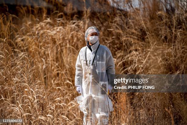 This picture taken on February 27, 2021 shows reverend Akira Sato wearing in protective suit as he poses outside the old building of the Fukushima...