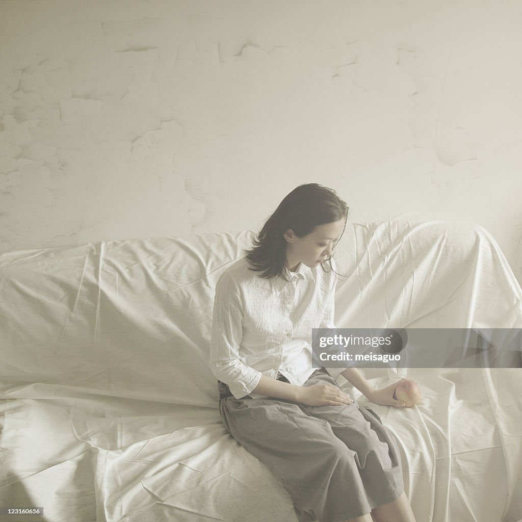 Woman sitting on sofa, holding apple