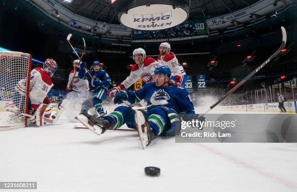 Jake Virtanen of the Vancouver Canucks gets hauled down by Jesperi Kotkaniemi of the Montreal Canadiens while battling for the loose puck during the...