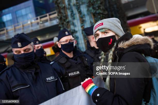 Protester in a hat with the world "Feminist" on it holds a banner during the protest. People took the streets in Warsaw on 8th of March in a protest...