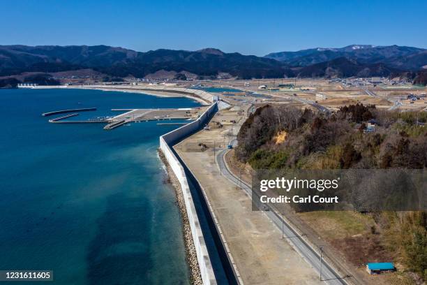 In this view from a drone, a huge, recently-built, concrete tsunami wall runs along the shoreline in Rikuzentakata where 1554 people were killed in...