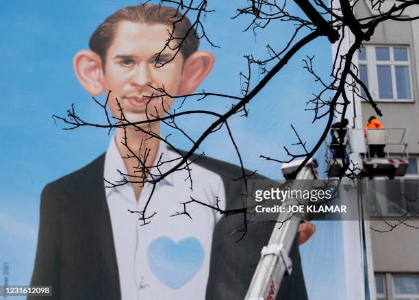 Workers attach a giant poster, created by the famous Austrian artist and caricaturist Gerhard Haderer, featuring Austrian Chancellor Sebastian Kurz,...