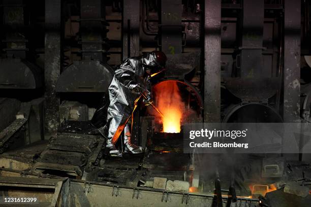 Worker wears heat resistant protective clothing while supervising the liquid copper molds at the KGHM Polska Miedz SA smelting plant in Glogow,...