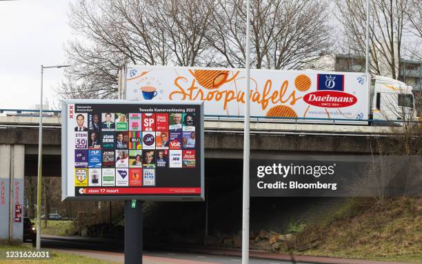 Daelmans Stroopwafels haulage truck passes near Dutch political party election campaign posters on a billboard in Amsterdam, Netherlands, on Tuesday,...