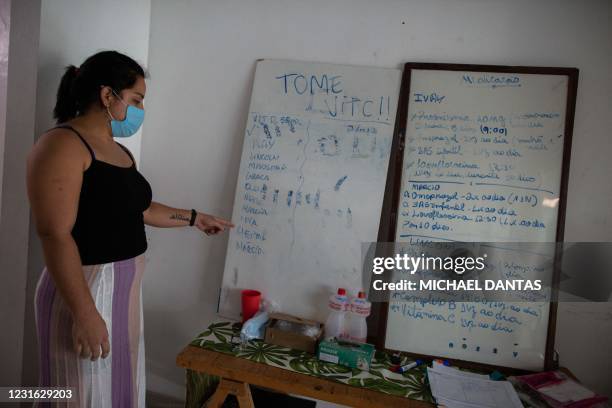 Student Lais de Souza Chaves who cares for eight family members at their home looks at an improvised medical chart in Manaus on January 28, 2021.
