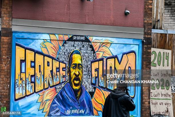 Man walks past the mural of George Floyd near the makeshift memorial of George Floyd before the third day of jury selection begins in the trial of...