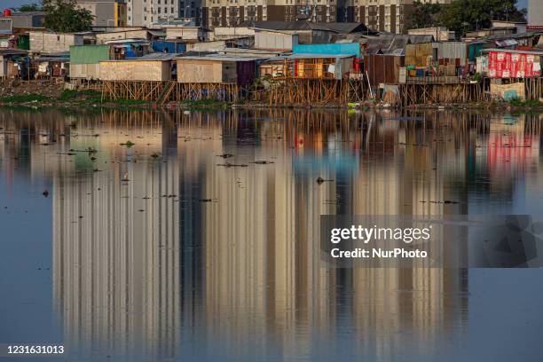 This picture shows a slum area and reflection of a building seen the Pluit dam in Jakarta on March 10, 2021. The Governor of Bank Indonesia Perry...
