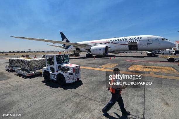 Workers unload a container from a plane of Aeromexico airline carrying the second shipment of the Sputnik V vaccines against COVID-19 from Russian...