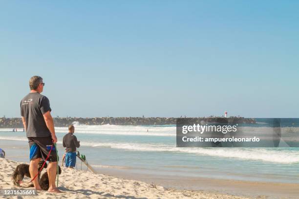 people enjoying the beach at the spit wharf - main beach, gold coast, queensland - main beach gold coast stock pictures, royalty-free photos & images