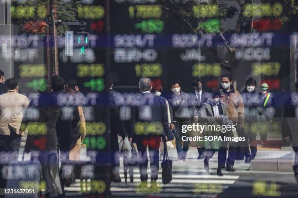 Cross road is being reflected by an electronic board showing Japans Nikkei 225 index and other indexes at a securities firm in Tokyo.