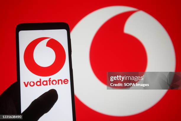 In this photo illustration, the Vodafone logo of a multinational telecommunications company seen displayed on a smartphone into a silhouette of a...