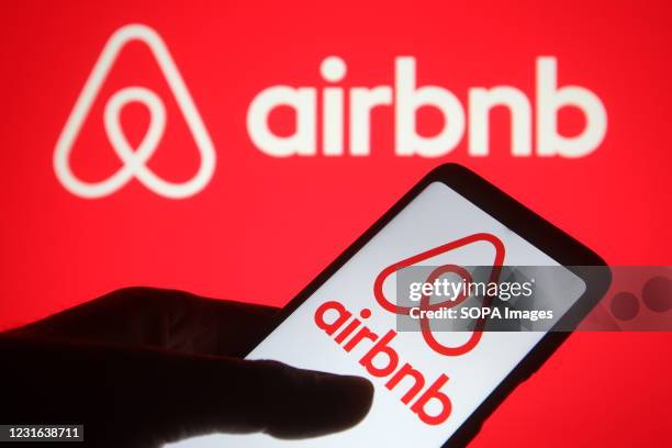 In this photo illustration, an Airbnb logo seen displayed on a smartphone and a pc screen.